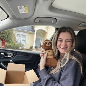 Person sitting in a car holding sloth socks